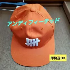 週末限定セール【UNDEFEATED】 オレンジ キャップ ホワイトロゴ
