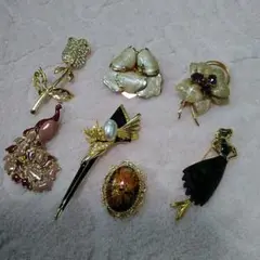 ゴールドの薔薇u0026孔雀u0026黒色u0026花模様u0026濃淡の黒色のドレスの7種類のブローチです。