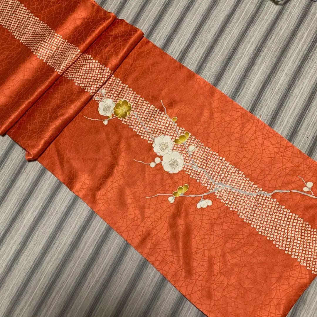 Thumbnail of Genuine silk fabric scraps, approximately 35cm x 130cm. Orange with floral and shibori patterns, possibly plum blossoms? Gold leaf accents.