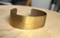 Gold-colored bangle with the inscription "TOMORROW IS ANOTHER DAY".