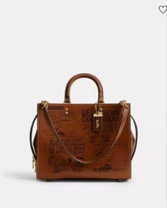 COACH X PEANUTSローグ バッグ・ニュースペーパー プリントブラウン COACH X PEANUTSローグ バッグ・ニュースペーパー プリント