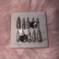 Silver glitter nail tips with Hello Kitty charms - perfect for a trendy, long nail look.