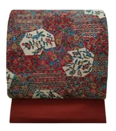 美品　名古屋帯　型染め　縮緬　全通柄　エンジ色の地　草花文様　幾何学模様