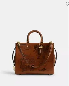 COACH X PEANUTSローグ バッグ・ニュースペーパー プリントブラウン