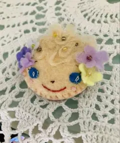 フェルト製顔型ブローチ 花飾り付き