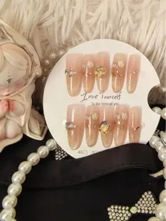 薄いピンクゴールドのラメグラデーションとフラワーデザイン、ストーンのネイルチップ