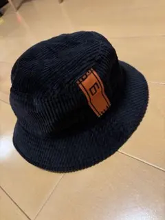 コーデュロイ バケットハット 黒 オレンジロゴ オーバーライド