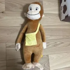 黄色のバックをかけたおさるのジョージぬいぐるみ