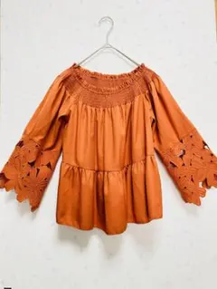 オレンジ色のオフショルダートップス