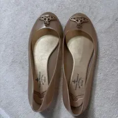 Light pink flat shoes with a metal logo.