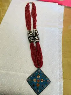 青いペンダントの赤いビーズネックレス