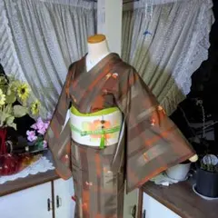 茶系のトーンに織り込まれた柄模様が蝶のように舞う、小粋な正絹紬のお着物です