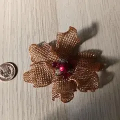 オレンジ色の花形ブローチ