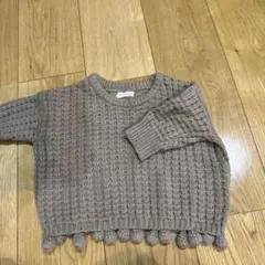 ポンポン付きグレーのニットセーター