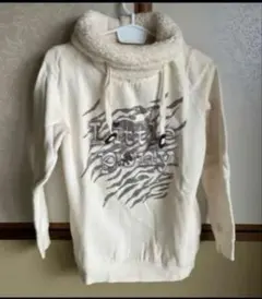 アイボリーのボア襟付き長袖トップス、グラフィックプリントデザイン。