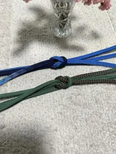 青と紺のグラデーションの帯締めと緑 に多色の編み込みデザインの帯締めの2点