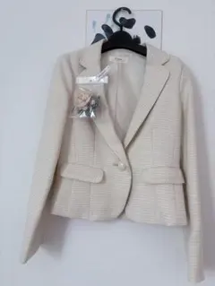 ベージュ テーラードジャケット 花のブローチ付き