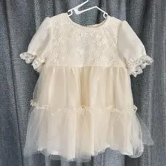 アイボリーの刺繍入りベビードレス、フリル付きの袖とチュールスカートが特徴。