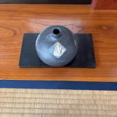 黒い陶器の花器、丸型、凹みあり